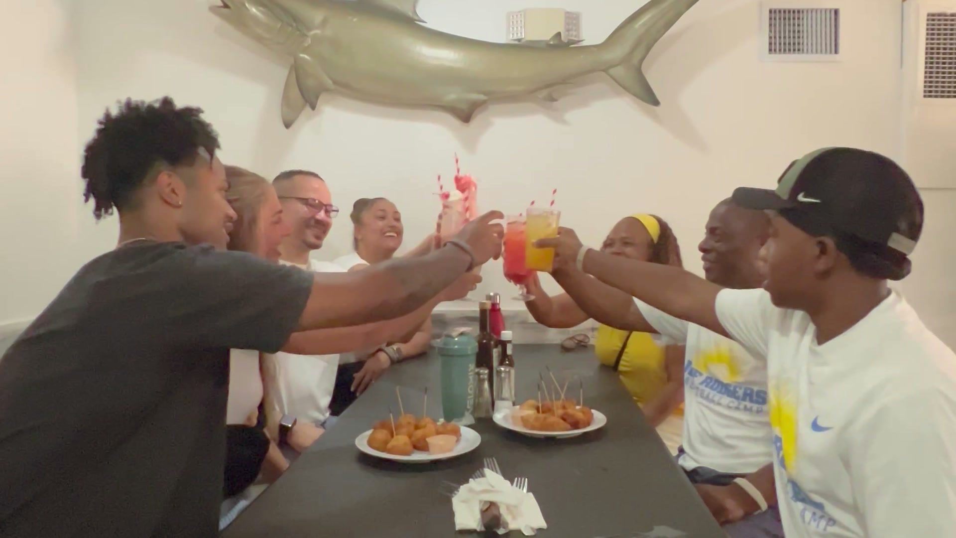 Guests toasting with frozen daiquiris over plates of conch fritters inside Twin Brothers, Arawak Cay.