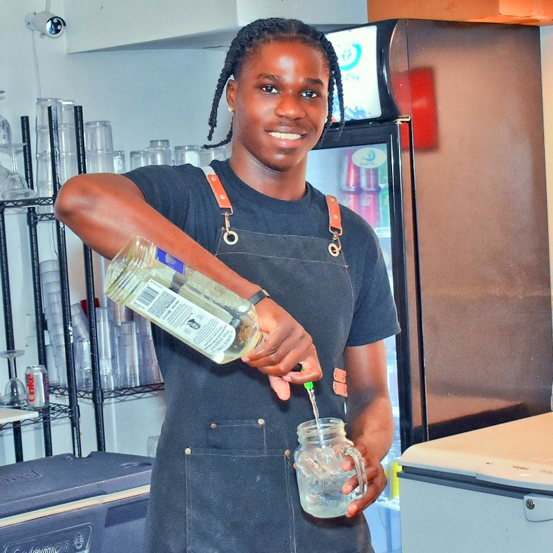 A Twin Brothers bartender pouring a drink into a mason jar behind the counter.
