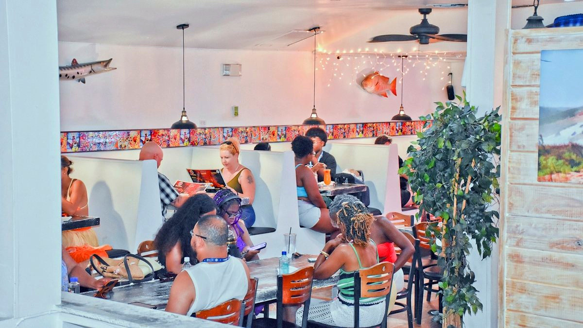 The renovated dining room at Twin Brothers, guests in white booths under strings of lights.