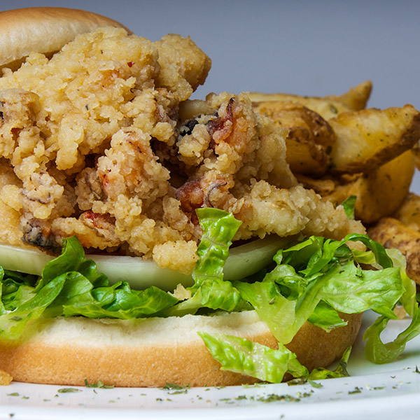 A cracked conch sandwich with lettuce and thick-cut fries