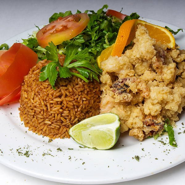 Cracked conch dinner with peas and rice, side salad, lime and orange