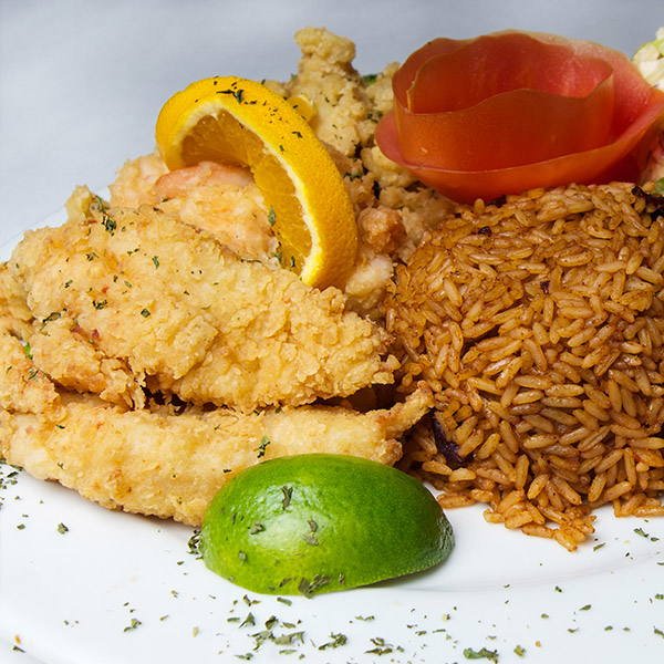 Fried seafood with peas and rice, tomato and a lime wedge