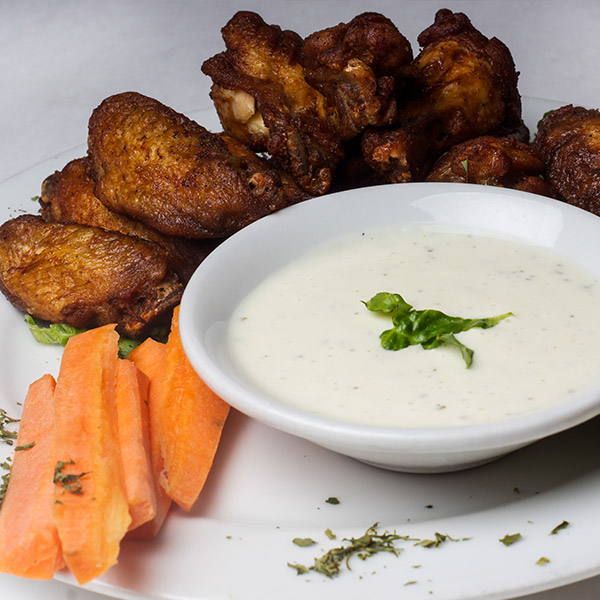 Fried chicken wings with a bowl of dip and carrot sticks